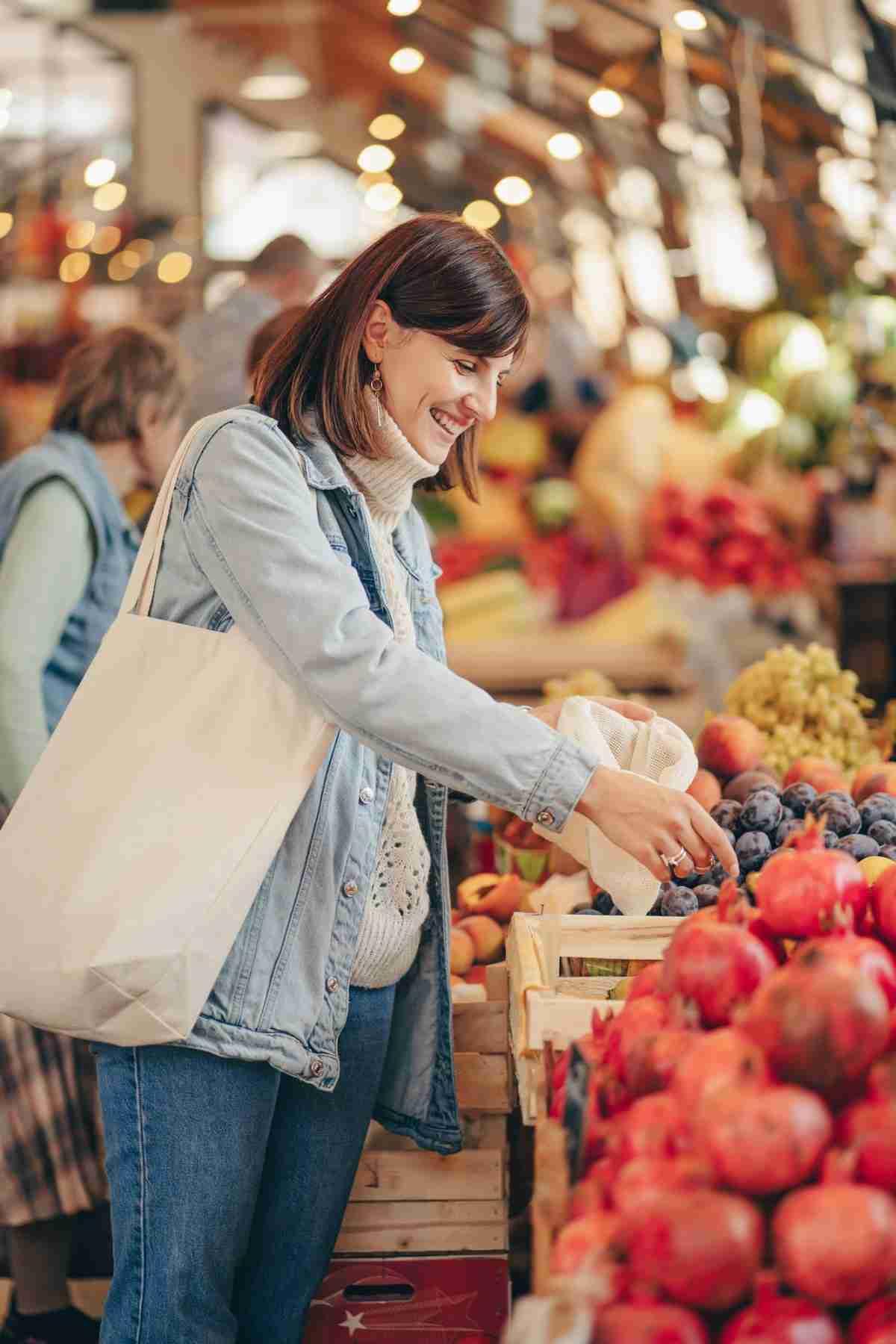 A woman shopping for fruits and vegetables in a grocery store.